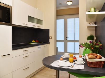 offene Küche mit Kochfeld, Mikrowelle und Geschirrspüler mit Esstisch und Bestuhlung