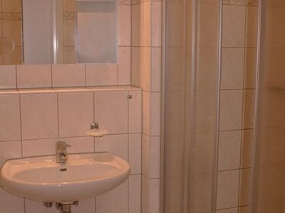 Badezimmer mit Dusche, Spiegel, WC und Waschbecken
