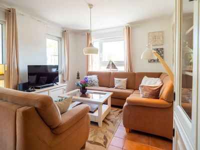 Wohnzimmer mit Sofasitzecke, Sessel und Sideboard mit TV