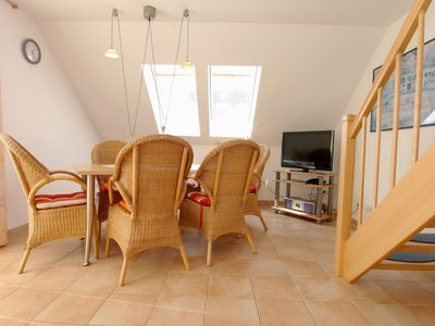 offener Wohnbereich mit Esstisch, Bestuhlung, Sideboard mit TV und Treppe in das DG