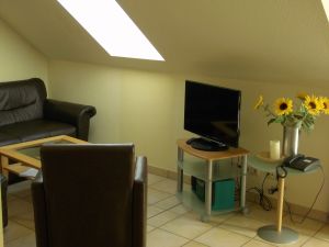 Wohnbereich mit Sitzecke, Sessel, Couchtisch, Sideboard und TV