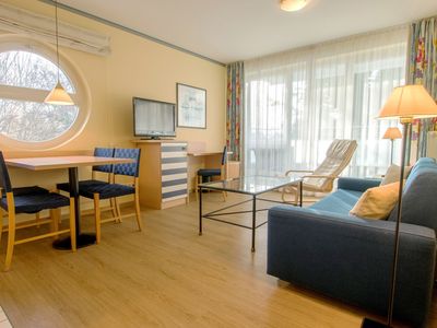 Wohnzimmer mit Sofa, Couchtisch und Sessel, Sideboard mit TV, Esstisch und Bestuhlung