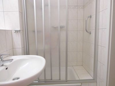 Badezimmer mit Dusche, Waschbecken, Spiegel und WC