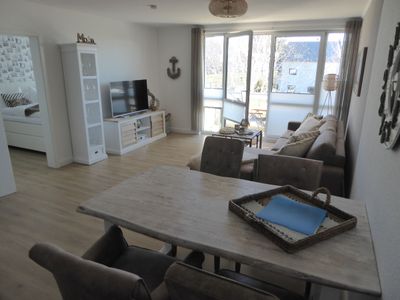 Blick in das Wohnzimmer mit Esstisch, Bestuhlung, Sofa, Regal, TV und Sideboard