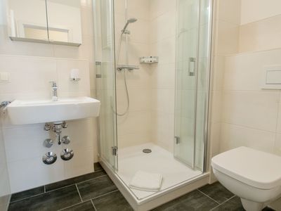 Badezimmer mit Dusche, Spiegel, WC und Waschbecken