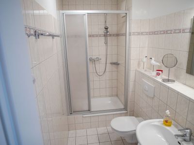Badezimmer mit Dusche, WC, Waschbecken und Spiegel