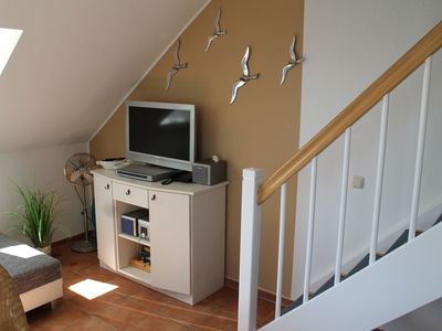 Wohnbereich mit Sideboard und TV mit anchließender Treppe ins DG