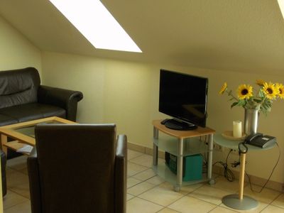 Wohnbereich mit Sitzecke, Sessel, Couchtisch, Sideboard und TV