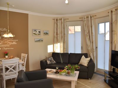 offener Wohnbereich mit Sofa, Sessel, Couchtisch, Sideboard mit TV, Esstisch und Bestuhlung