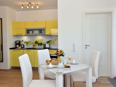 Esstisch mit Bestuhlung und Blick in die offene Küche