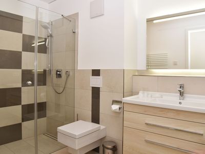 Badezimmer mit Dusche, WC, Waschbecken und Spiegel
