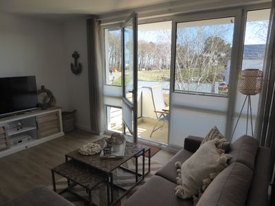 Sideboard, TV, Sofa, Couchtisch mit Blick vom Wohnzimmer auf den Balkon und Deichpromenade