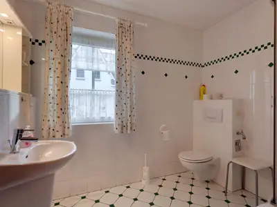 Das Bad empfängt Sie mit einer ebenerdigen Dusche aus Glas.