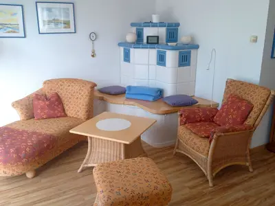 Wohnbereich mit Sofa, Sessel und Elektrokamin