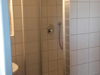 Blick ins Bad, links das Waschbecken, daneben Dusche und WC