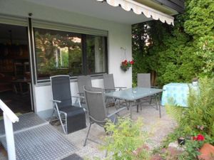 Sonnige Terrasse mit Gartenmöbeln und Sonnenschutz