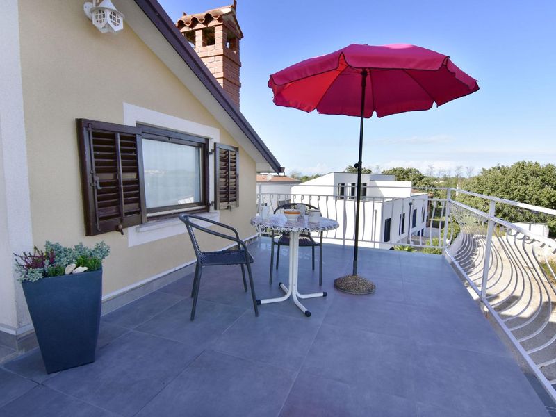 Die Terrasse mit Tisch, Stühlen und Sonnenschirm am Eingang der Wohnung