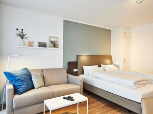 Wohn/Essbereich mit Couch, Doppelbett und Kleiderschrank
