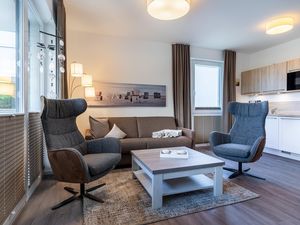 Wohn-/Essbereich mit Doppelschlafcouch, Couchtisch, Sessel und Küchenzeile
