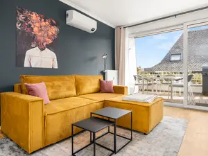 Wohnzimmer mit Schlafcouch und direktem Zugang zum Balkon