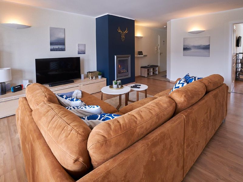 Wohnbereich. Großer, gemütlicher Wohnbereich mit Kamin, UHD-Fernseher, Switch-Konsole und komfortabler XXL-Couch.