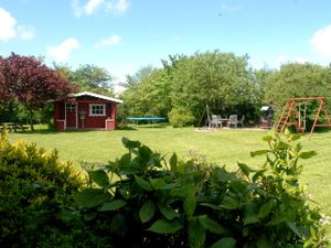 Blick in den großen Garten mit Gartenhaus, Grillplatz und Spielgeräten