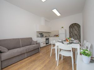 Wohnzimmer mit Sofa, Esstisch und Küche
