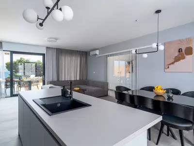 Ein Essbereich mit Glastür zum Poolbereich und direktem Ausgang zum überdachten Essbereich im Freien