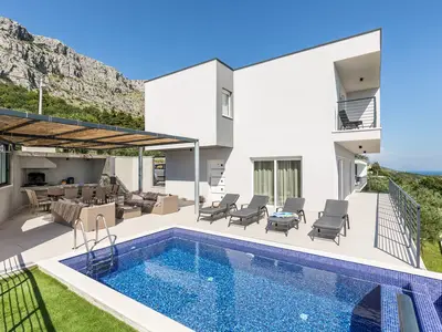 Privater beheizter Pool mit Infinity-Rand und bequemen Liegestühlen