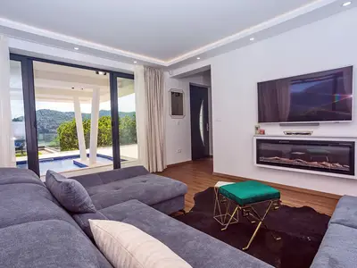 There is a living room with a flat-screen TV and direct approach to the pool and outdoor dining area
