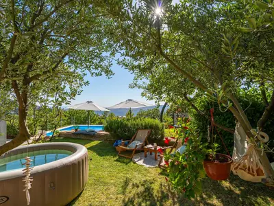 Rasenfläche mit Softub-Whirlpool, eine Lounge-Ecke unter den Olivenbäumen als perfekter Ort zum Lesen und Entspannen