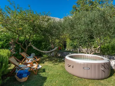 Rasenfläche mit Softub-Whirlpool, eine Lounge-Ecke unter den Olivenbäumen als perfekter Ort zum Lesen und Entspannen