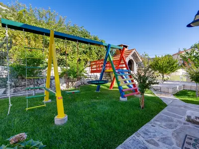 Spielplatz mit Schaukel und Rutsche neben Grill
