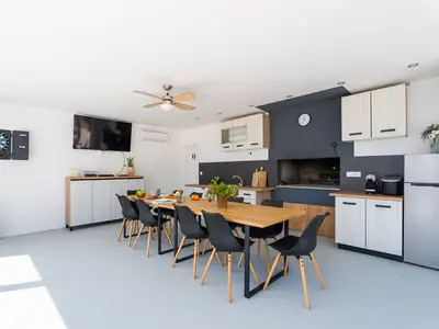 Eine Sommerküche mit Esstisch, Geschirrspüler, Fernseher und Darts