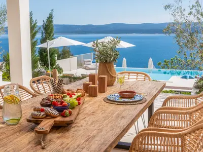 Ein Ess- und Grillplatz im Freien mit einem Esstisch aus Holz für 10 Personen, einer stilvollen Lounge-Ecke und einem Grill (Holz/Holzkohle)