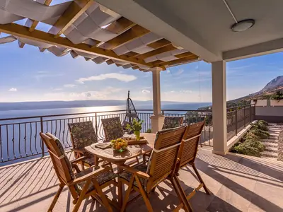 Überdachter Essbereich im Freien mit Gasgrill mit Panoramablick auf das Meer und die Insel
