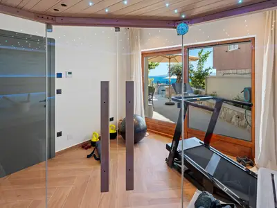 Der finnische Saunaraum (15 m2) mit Dusche, Laufband, Pilates-Gerät und Glastüren zum Außenbereich und zum Pool