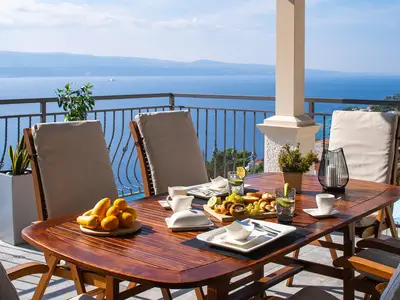 Der geräumige Balkon mit einem Esstisch im Freien bietet den perfekten Rahmen für Mahlzeiten mit atemberaubendem Meerblick