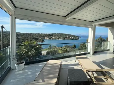 Der neu überdachte, moderne Balkon im ersten Stock bietet einen atemberaubenden Blick auf eine ruhige Bucht, umgeben von üppigem Grün.