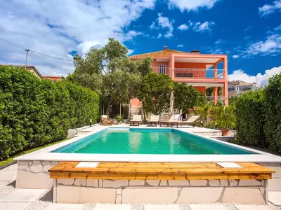 Poolbereich mit grünem Zaun vor der Villa