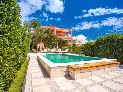 Poolbereich mit grünem Zaun vor der Villa