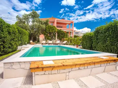 Poolbereich mit grünem Zaun vor der Villa