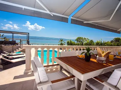Essbereich im Freien mit Meer- und Poolblick, verbunden mit einer Küche