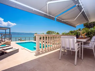 Essbereich im Freien mit Meer- und Poolblick, verbunden mit einer Küche