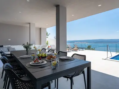 Ein offener Wohnbereich mit einem überdachten Essbereich im Freien mit Grill und einer Lounge-Ecke.