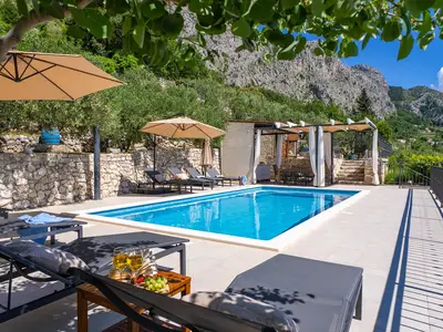 Pool area surrounded by nature, offering stunning mountain and a sea view. 
