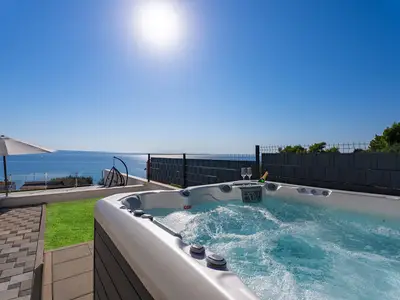 Ein Hot-Tub (ein Whirlpool) neben dem überdachten Essbereich im Freien (ein paar Stufen über dem Pool und der Sonnenterrasse)
