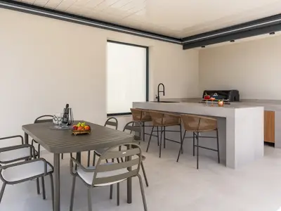 Überdachter Essbereich für 8 Personen und eine Küchenzeile mit Gasgrill