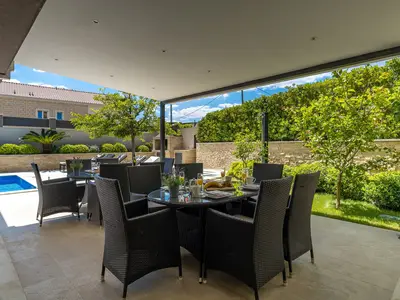 Essbereich im Freien im Schatten, neben dem Pool und dem Grill