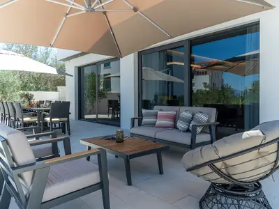 Outdoor dining area with the barbecue, a lounge corner, two sun umbrellas and nice sea views